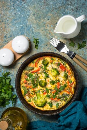 Frittata with fresh vegetables. Baked omelette with broccoli, paprika, brussels sprouts, green beans and herbs. Top view with copy space.の写真素材
