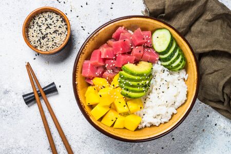 Tuna poke bowl with rice, avocado, mango and cucumber on white table.の写真素材