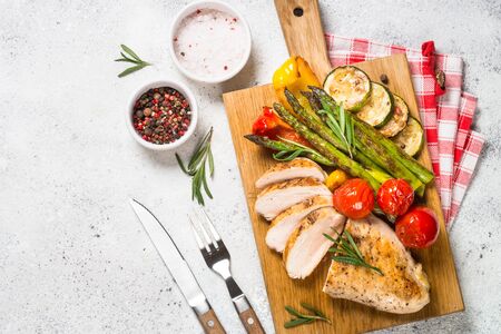 Chicken breast grilled with vegetables on a wooden serving board.の写真素材