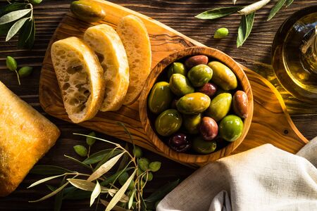 Olives, olive oil and ciabatta on wooden table.の写真素材