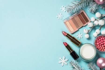 Makeup products, skincare product with christmas decorations. Idea for christmas shopping, presents. Top view on blue background.の写真素材