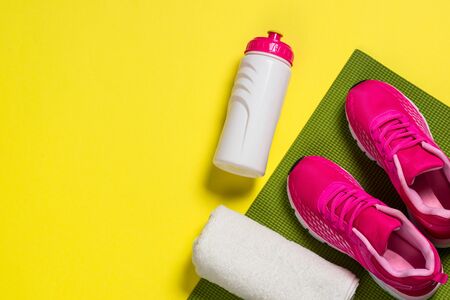 Sport equipment flat lay image on color background. Sneakers, towel, yoga mat and bottle of water. Trayning, workout and fitness concept.の写真素材