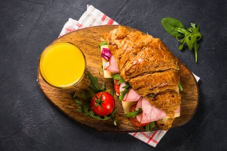 Croissant sandwich on black table.