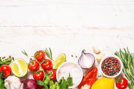 Food cooking background on white wooden table. Fresh vegetables, spices, herbs and oil. Ingredients for cooking with space for your text.の写真素材
