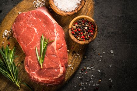 Beef steak on black background. Fresh beef steak striploin uncooked meat with ingredients for cooking. Top view with copy space.の写真素材