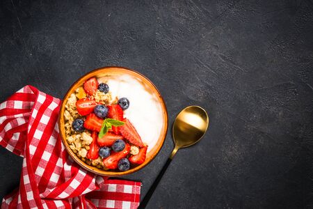 Greek yogurt granola with fresh berries on black stone table.の写真素材