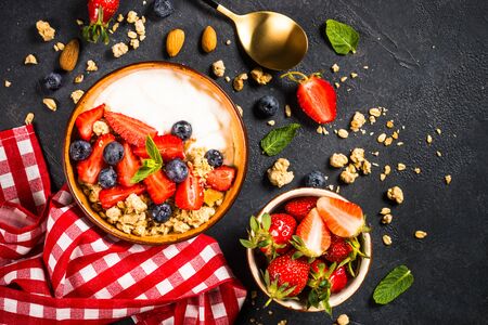 Greek yogurt granola with fresh berries on black stone table.の写真素材