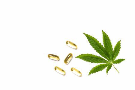 Cannabis oil, pills and green leaves at white table.の写真素材