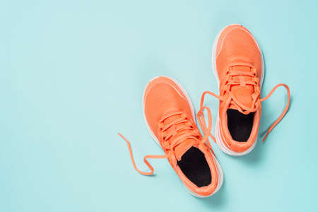 Pink sneakers at blue background top view.
