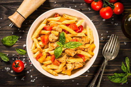 Pasta with chicken and vegetables at wooden table.の写真素材