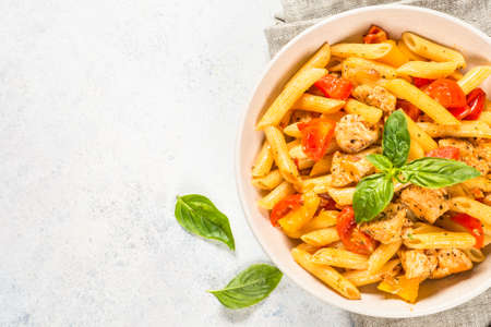 Pasta with chicken and vegetables at white table.の写真素材