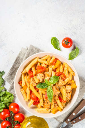 Pasta with chicken and vegetables at white table.の写真素材