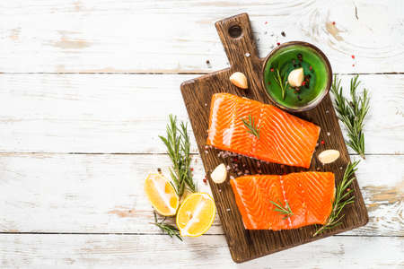 Salmon fish with ingredients at white table.の写真素材
