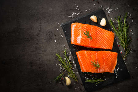 Salmon fish with ingredients at black table.の写真素材