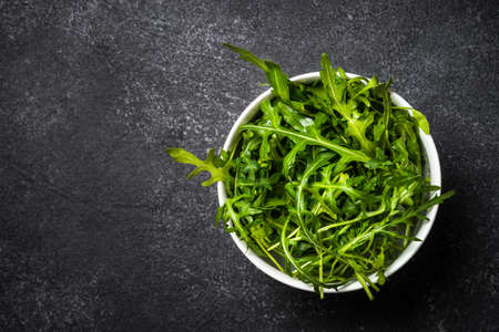 Arugula fresh green leaves at black stone table.の写真素材