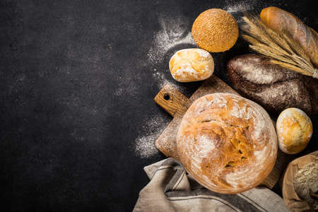 Fresh bread and buns at black table.