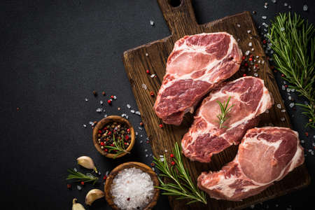 Pork meat at wooden board on black table.の写真素材