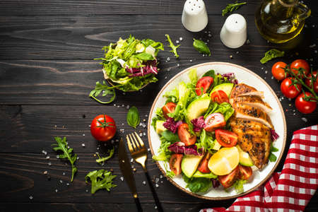 Grilled chicken with fresh salad at wooden table.の写真素材