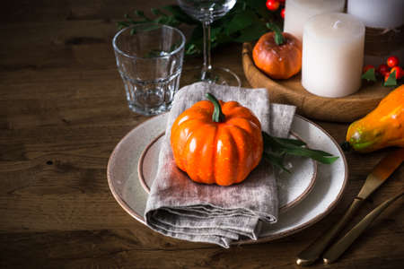 Autumn table setting with plate, pumpkin and candles.の写真素材