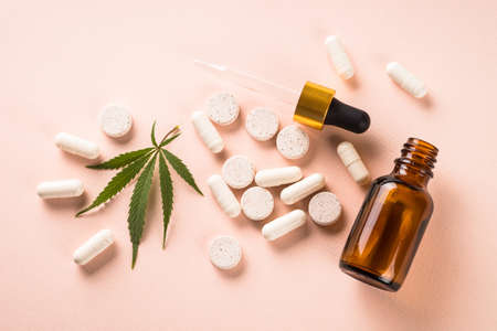 CBD oil in glass bottles and cannabis leaves at white table.の写真素材
