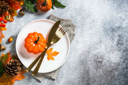Autumn table setting with white plate, golden cutlery and fall decorations.の写真素材