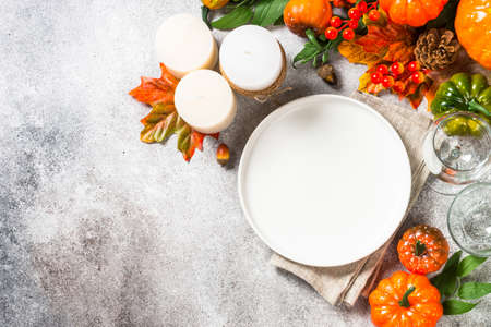 Autumn table setting with white plate, candles and fall decorations.の写真素材