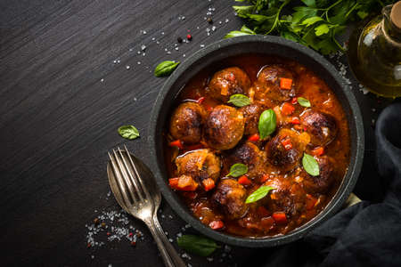 Meatballs in tomato sauce in a frying pan on dark stone table.の写真素材