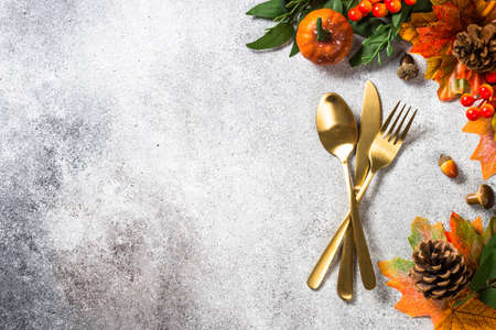 Gold cutlery and autumn decorations at stone kitchen table.の写真素材