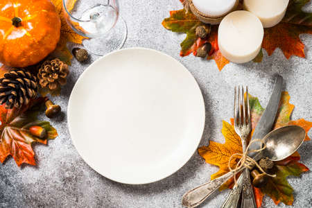 Autumn table setting with white plate, candles and fall decorations.の写真素材