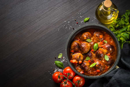 Meatballs in tomato sauce in a frying pan on dark stone table.の写真素材
