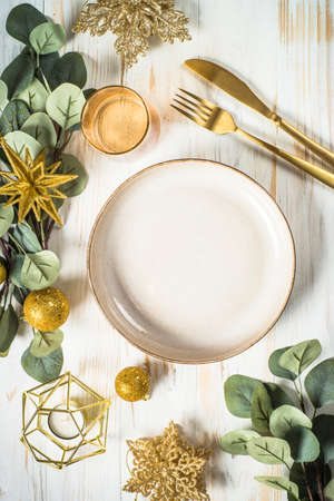 Christmas table setting with eucalyptus leaves and golden decorations.の写真素材