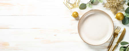 Christmas table setting with eucalyptus leaves and golden decorations.の写真素材