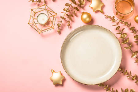 Christmas table setting with eucalyptus leaves and luxury metallic golden decorations at pink layout.の写真素材