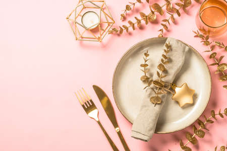 Christmas table setting with eucalyptus leaves and luxury metallic golden decorations at pink layout.の写真素材