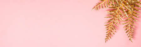 Golden palm leaves at pink background flat lay.