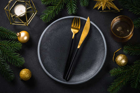 Christmas table setting with holiday decorations at black background.の写真素材