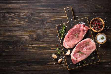 Fresh steaks with herbs and spices at black background.の写真素材