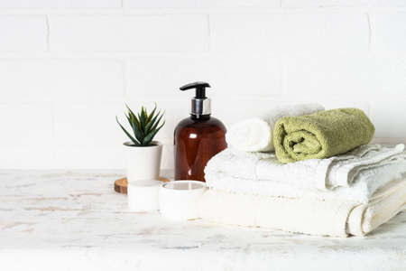 Bottle of soap and stack of towels in white bathroom.の写真素材