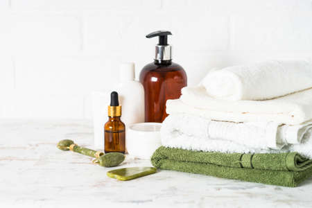 Bottle of soap and stack of towels in white bathroom.