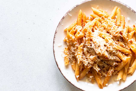 Italian pasta with tomato sauce, basil and parmesan cheese on white table.の写真素材