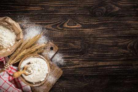 Wheat flour in a bowl on a wooden rustic background with spikelets.の写真素材