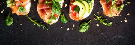 Open sandwich set with cream cheese, prosciutto, salmon, avocado and fresh greens.の写真素材