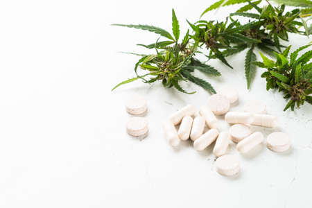 CBD oil in glass bottles and cannabis leaves at white table.の写真素材