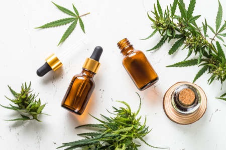 CBD oil and cannabis leaves at white table.の写真素材