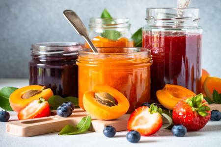 Homemade jam in glass jars at white table.