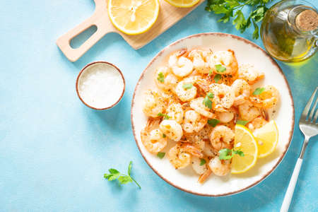 Fried shrimps with herbs and olive oil at blue table.の写真素材