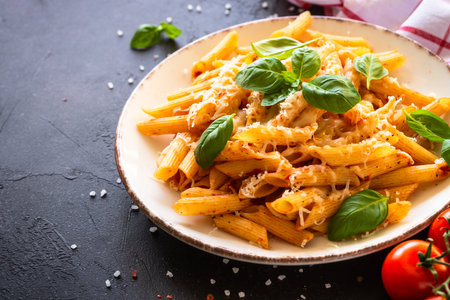 Italian pasta with tomato sauce, basil and parmesan cheese on dark table.の写真素材