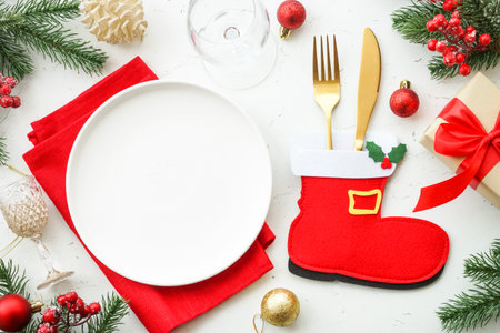 Christmas table setting. White plate, cutlery, red and golden decorations.の写真素材