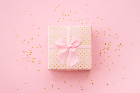 Gift box with ribbon and confetti on pink background.の写真素材