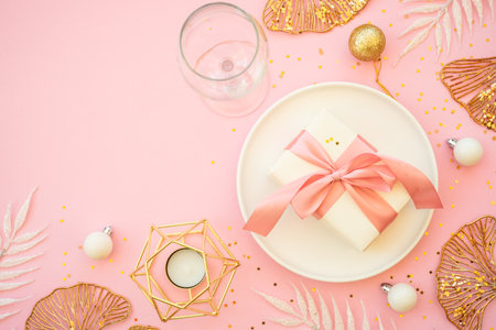 Christmas table setting with white plate and christmas golden decorations on pink background.の写真素材